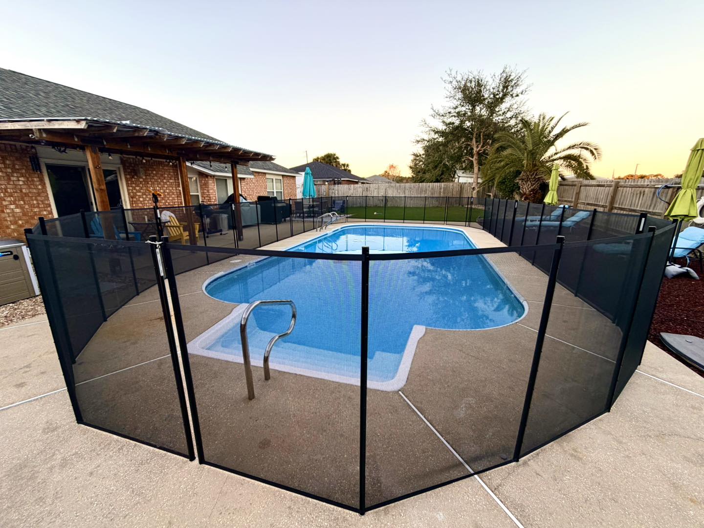 Removable mesh pool safety fence installed around a swimming pool in Navarre Florida